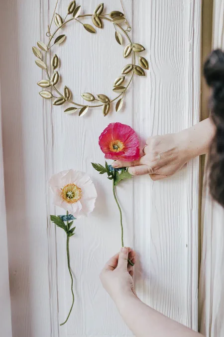 2 fleurs de pavot en papier collés au mur avec une couronne de feuillage