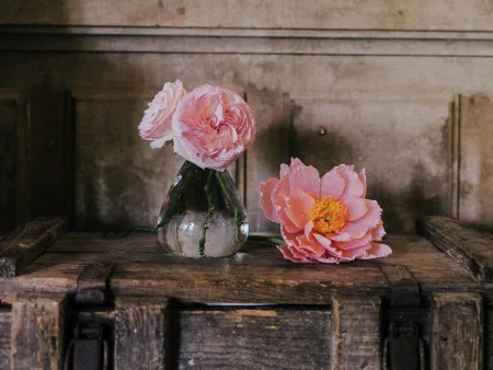 fleurs de pivoine en papier et roses fraîches sur un coffre en bois